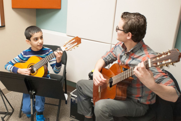 Guitar teacher working with young guitar student during lesson at Minnesota School of Music